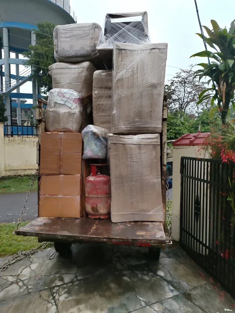 Agarwal Packers and Movers worker moving a stretch-wrapped armchair on a trolley during a home shift in Dehradun